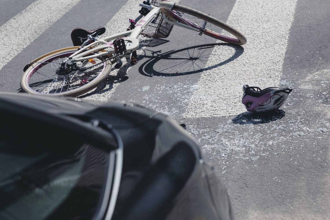 bicycle laying on road next to a car