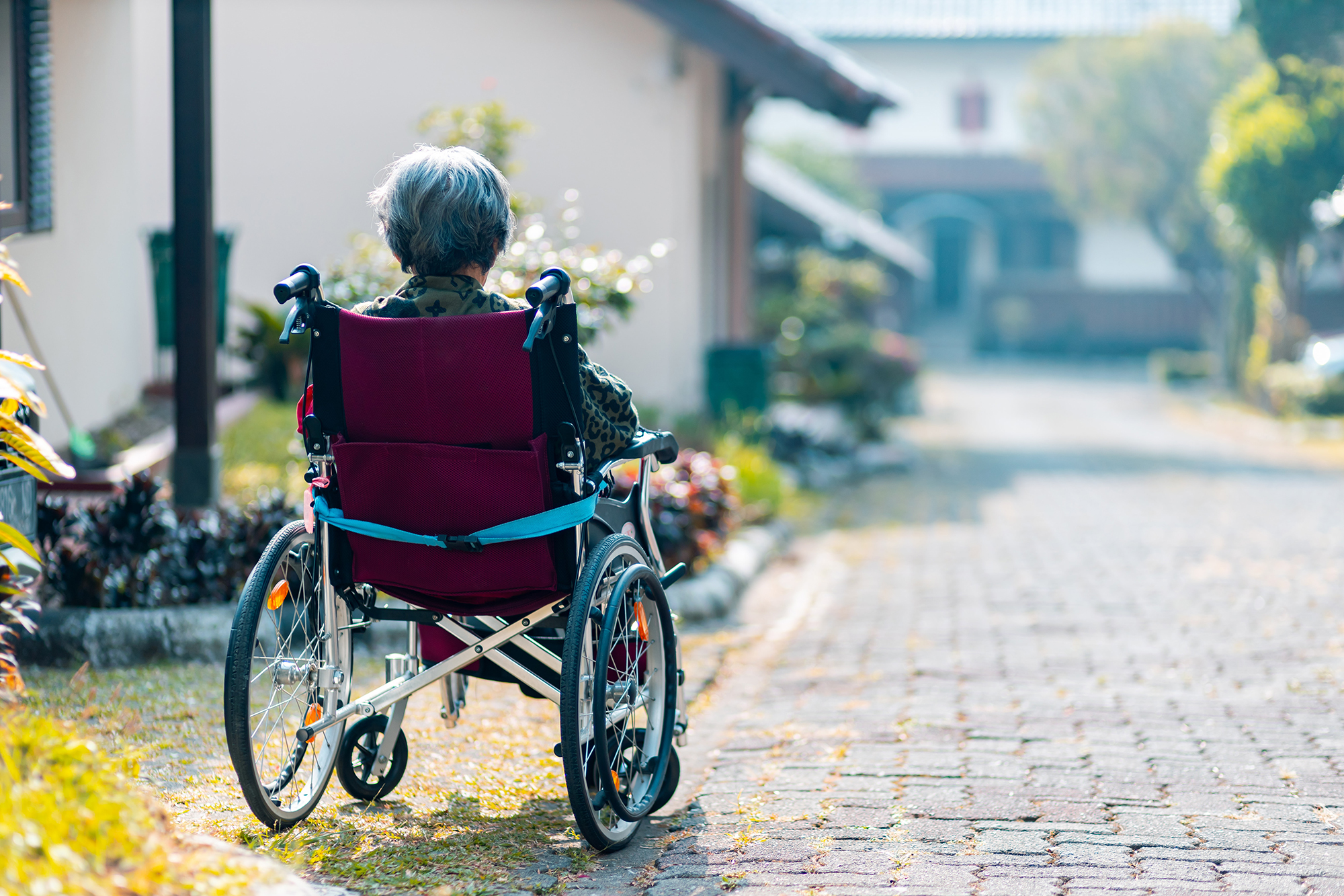 elderly woman sitting in wheelchair in alley