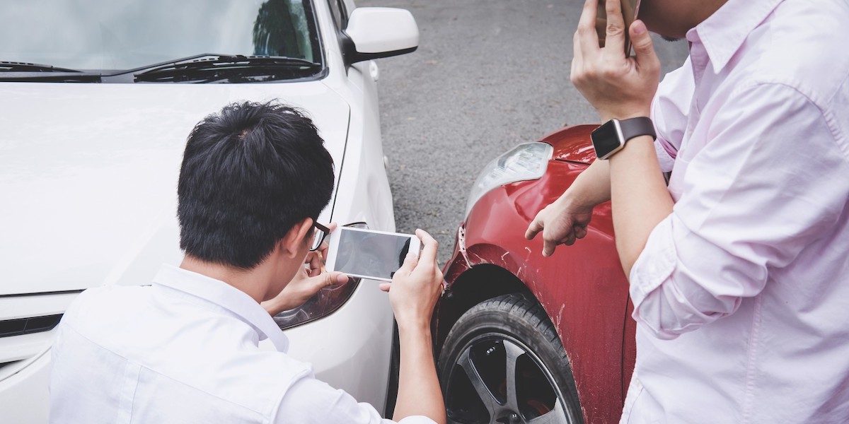 men taking photo and talking after car accident